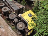 Pessoas que passavam pelo trecho duplicado viram o caminhão caído dentro do rio